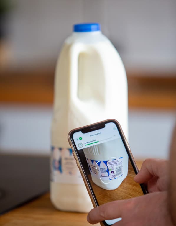 Photo of a smartphone scanning a QR code on milk packaging.