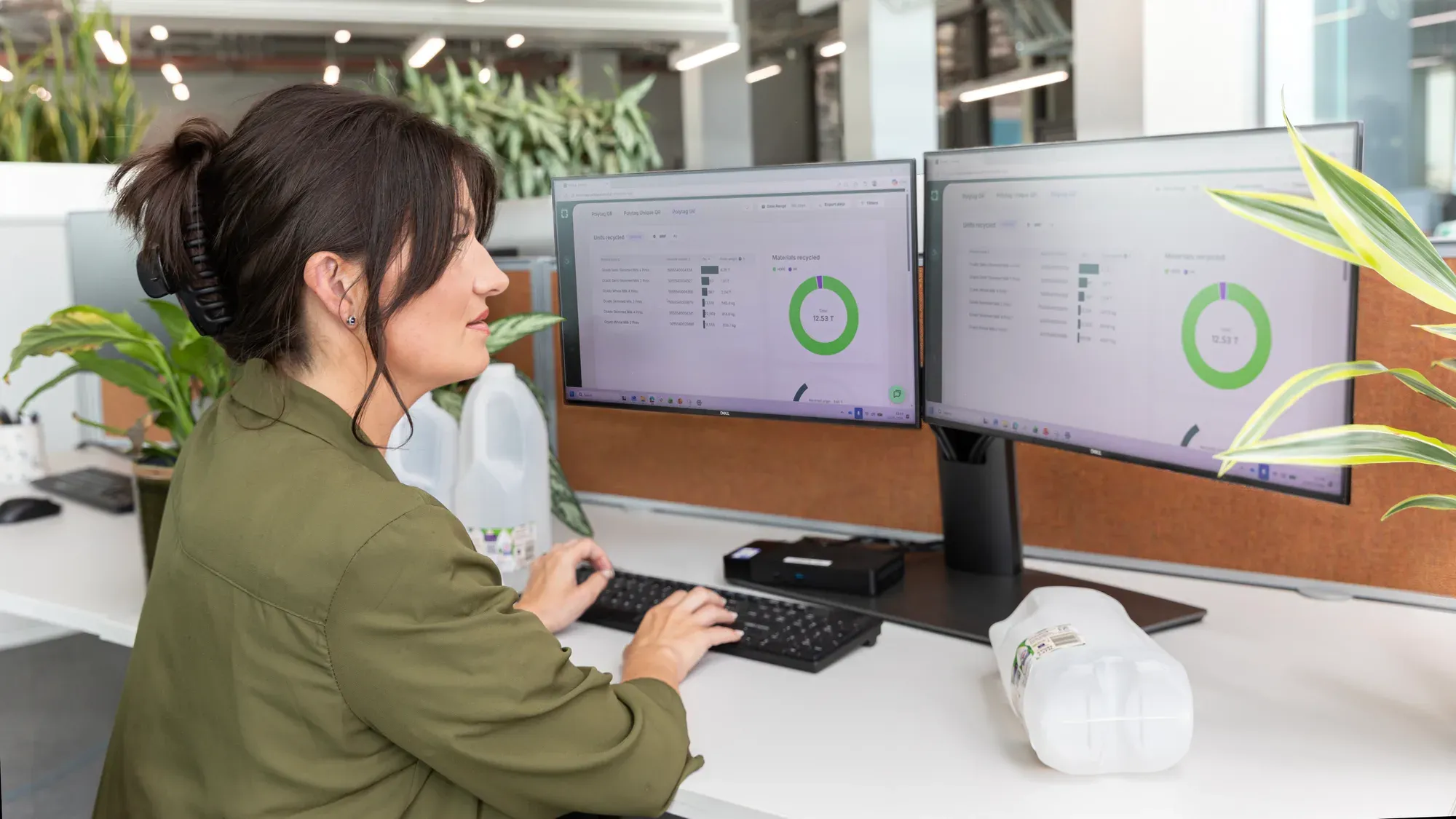 A Polytag team member at her desk with the dashboard on two screens, showing units and materials recycled