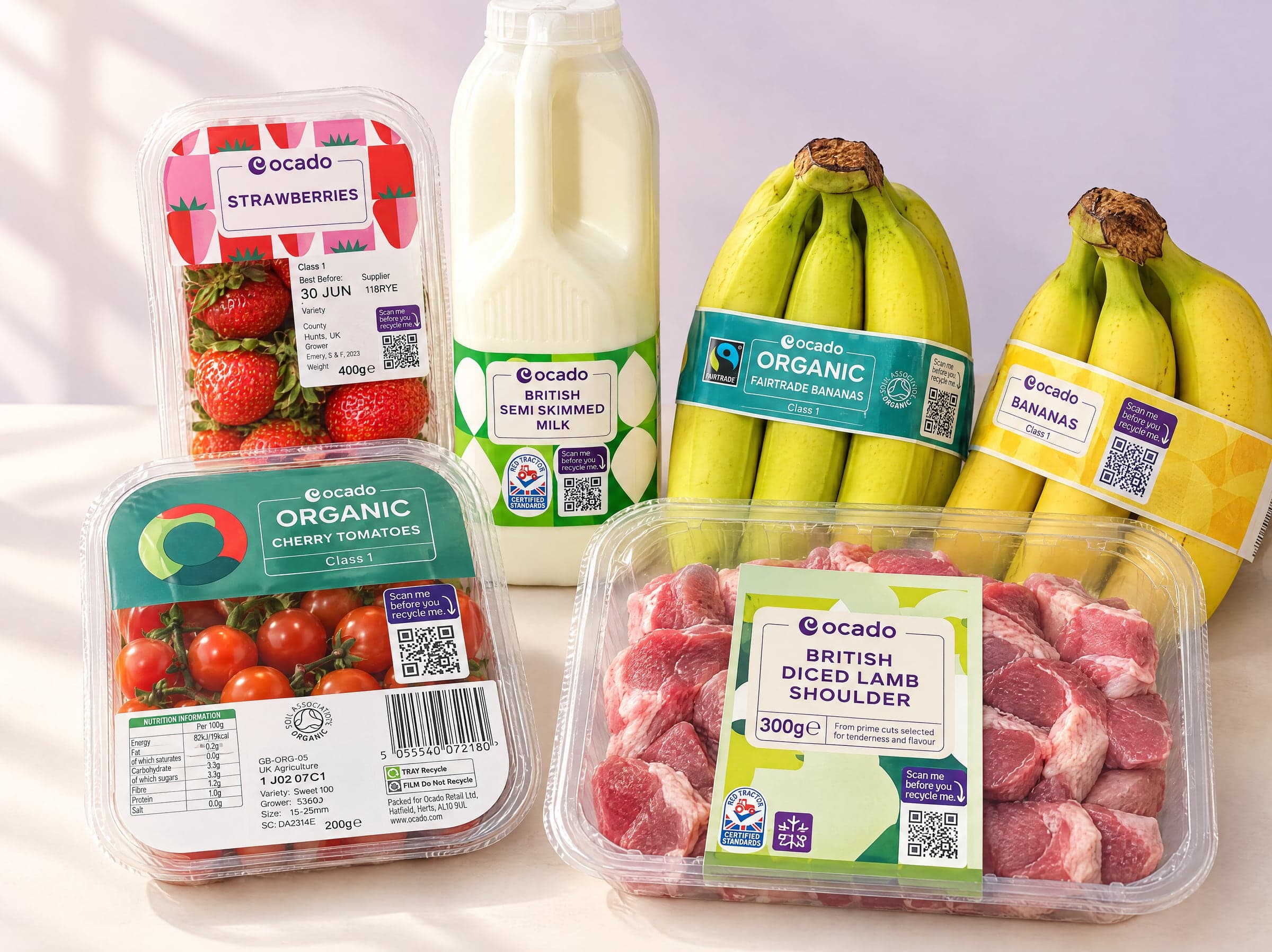 Ocado own-label strawberries, cherry tomatoes, semi-skimmed milk, bananas and diced lamb, each pack carrying a "Scan me before you recycle me" Smart QR Code