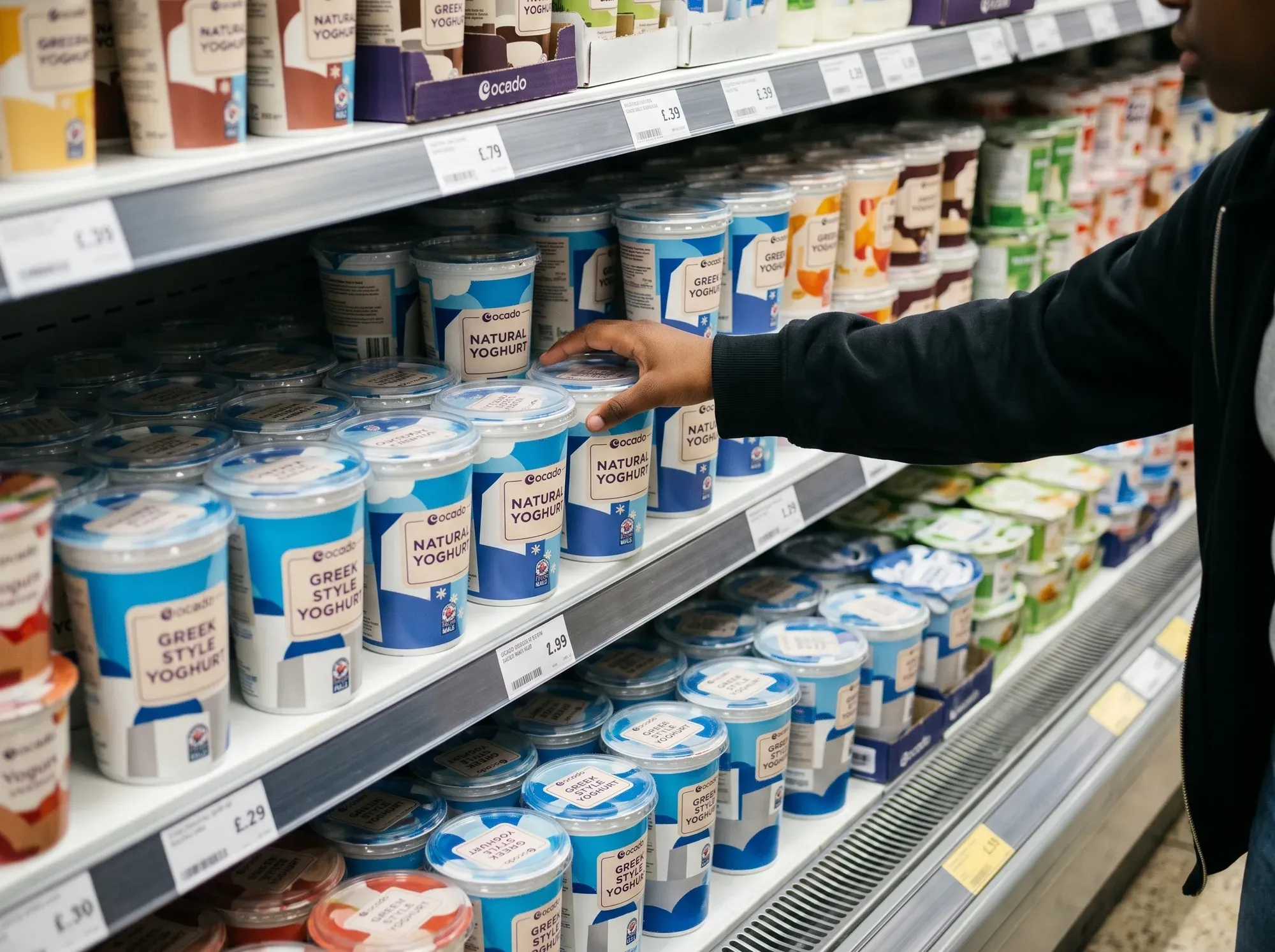 A shopper reaching for Ocado own-label yoghurt in a supermarket chiller