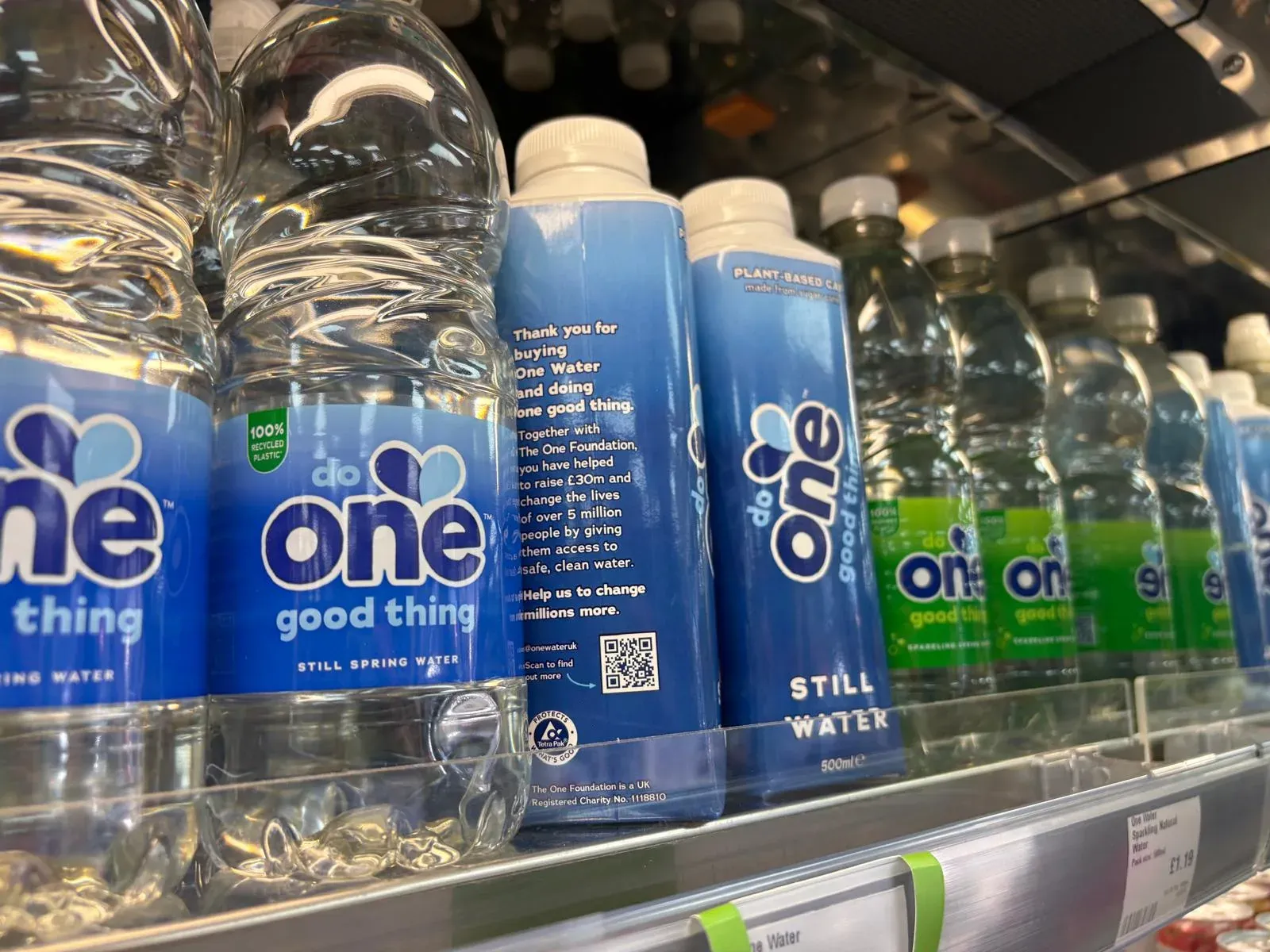 One Water bottles and cartons on a store shelf, a QR code printed on the carton
