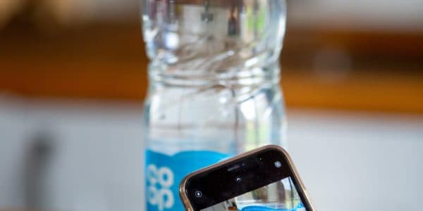 Photo of smartphone in front of coop plastic bottle