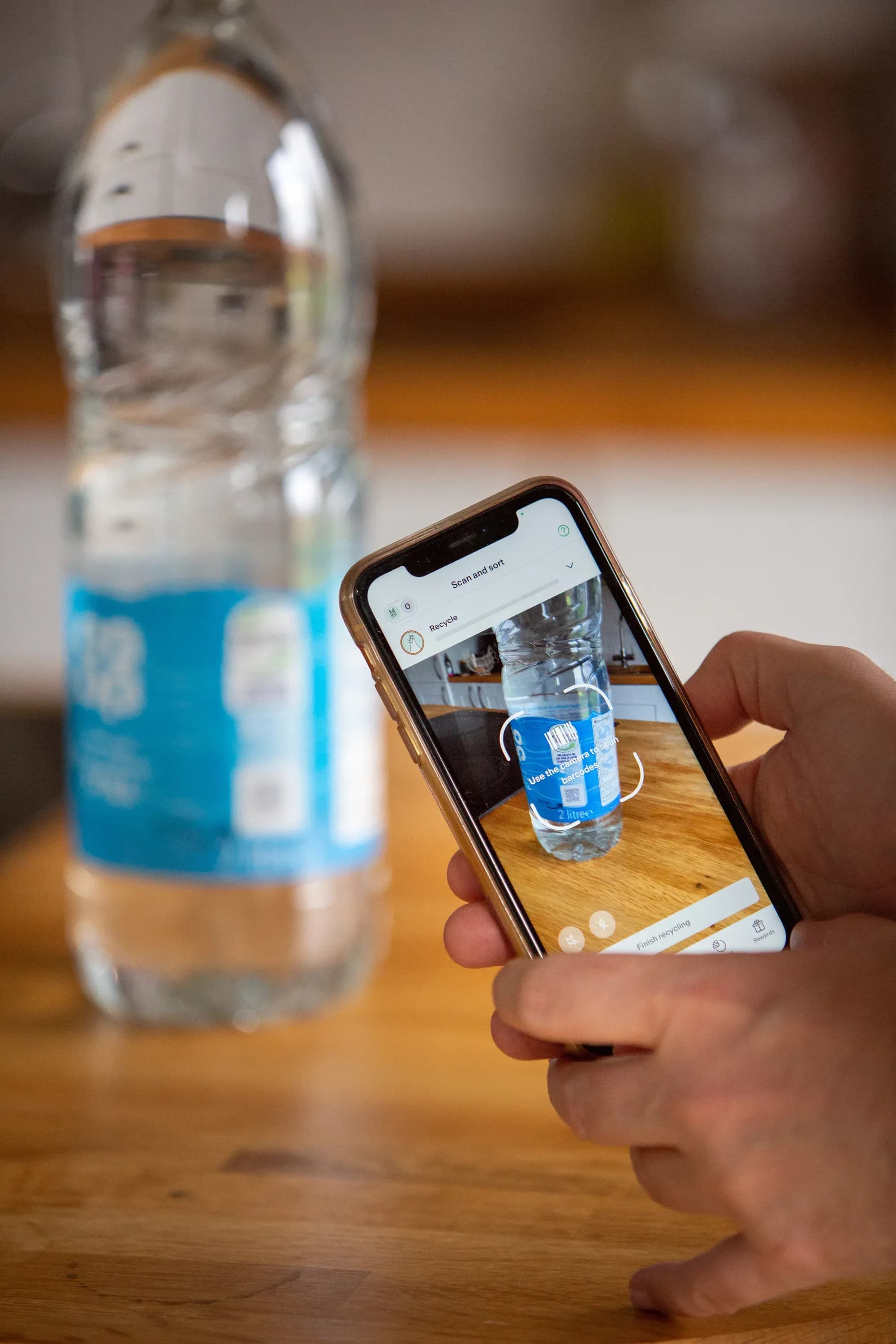 A phone scanning a Co-op water bottle on a kitchen worktop