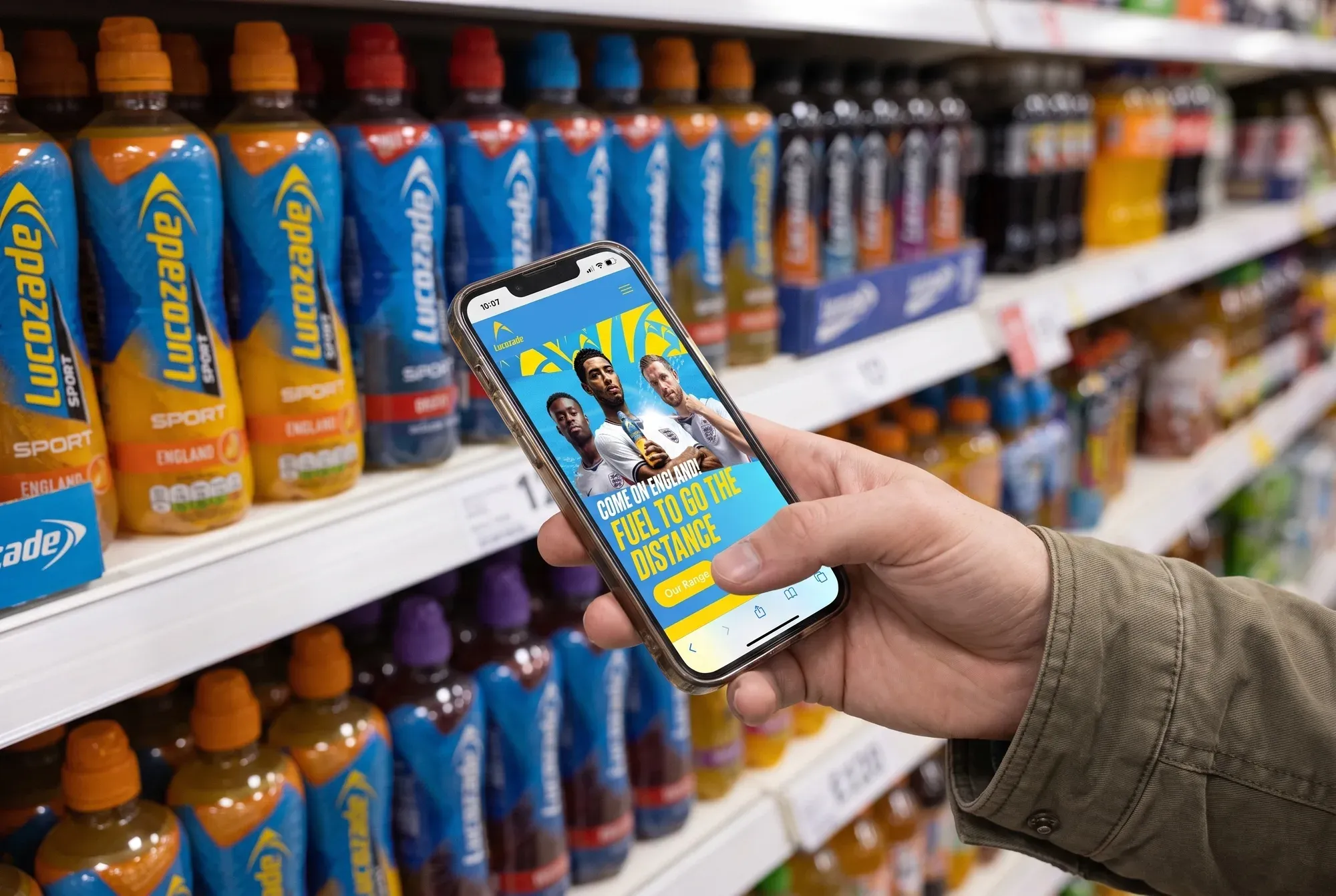 Lucozade's England campaign landing page open on a phone in front of a shelf of Lucozade Sport