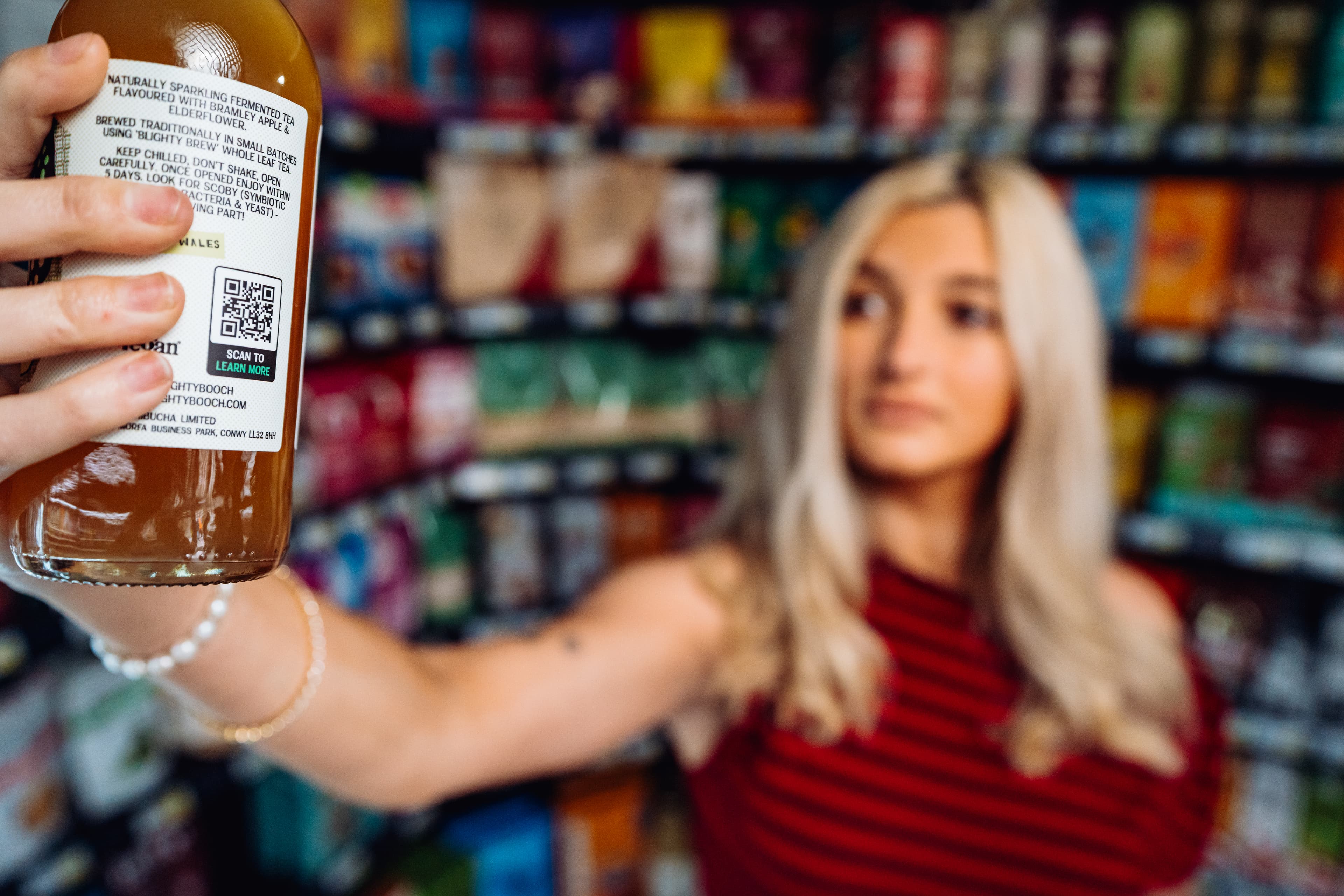 A bottle's Smart QR Code held up in a shop aisle