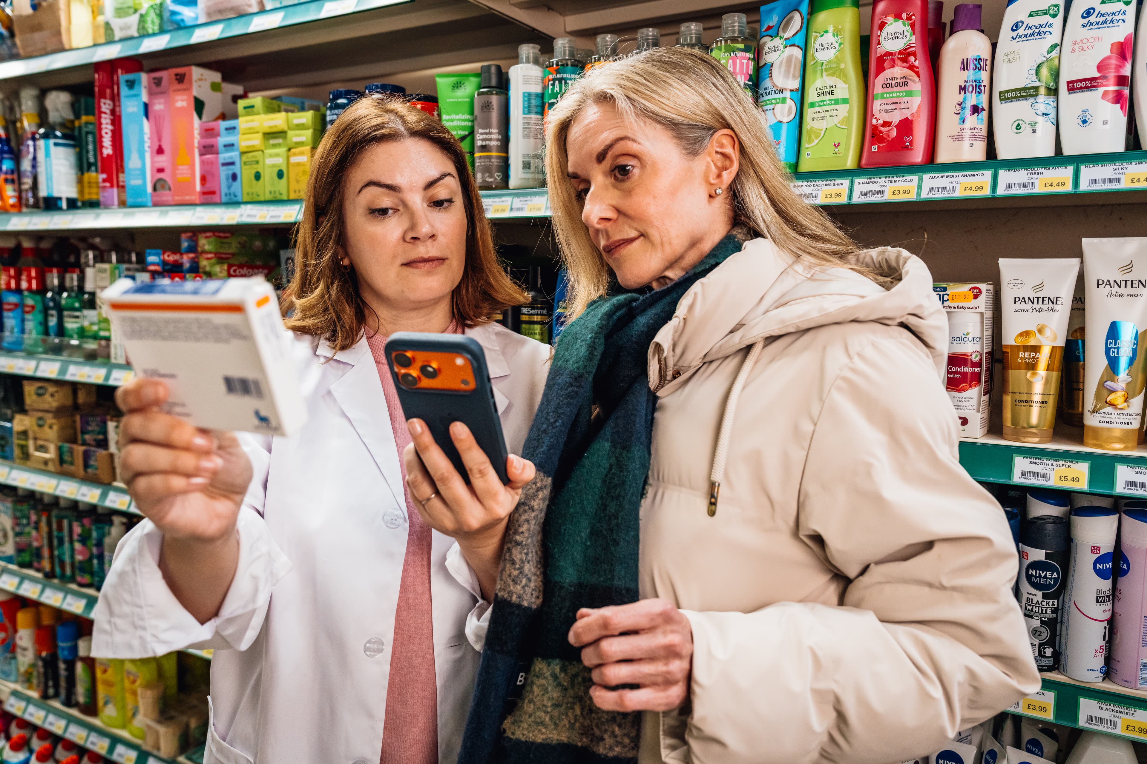 Two people reading a pack's label and a phone together